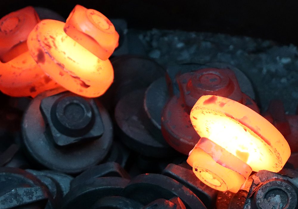 A ball valve blank at forging heat, white-hot in the centre.